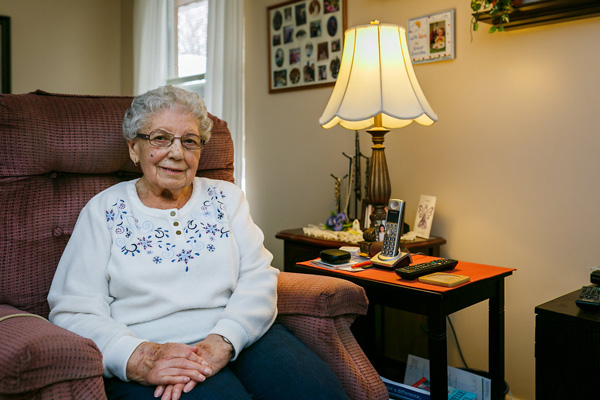 testimonial Smiling Elderly Woman Sitting Next to a Lamp